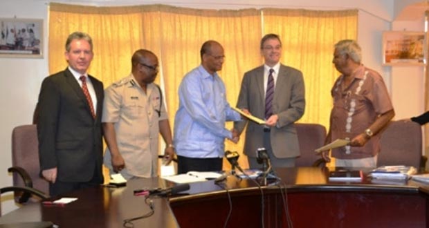 Home Affairs Minister Clement Rohee presents contract to Associate Director of  Capita Symonds, Paul Wadsworth after signing it. Also in photo are Police Commissioner Leroy Brumell and British High Commissioner Andrew Ayre
