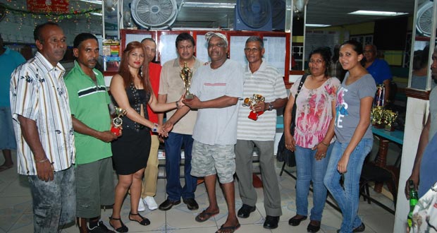 OVERSEAS-based Sandra Khan hands over the winning trophy to Ramroop ‘Spoon’ Sukhai. Sponsor Mohamed Hussein ‘Bobby’ Bacchus is at centre.