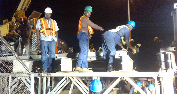 Workers atop and below the Demerara Harbour Bridge as all hands are on deck in getting the job done