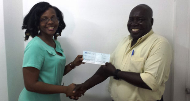 The Assistant Public Relations and Communications Officer, Wadecia Donald hands over the cheque valued at $100,000 to Winston Prince, representative of the Guyana Karate College.