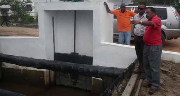 Minister Alli Baksh with PS George Jarvis inspecting the new sluice at Charity