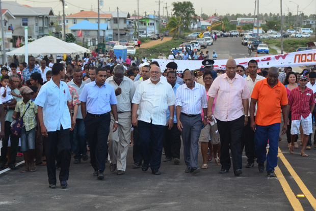 President Donald Ramotar, centre, flanked by Government Ministers and residents of Hope during a walk over the newly commissioned bridge