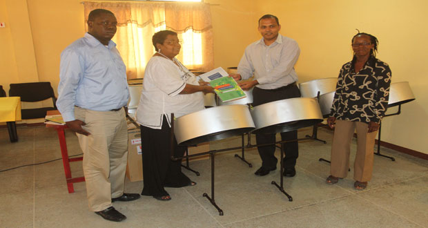 Minister Frank Anthony receives the masquerade manuals from UNESCO’s Inge Nathoo as the National School of Music’s Andrew Tyndall and National School of Dance’s Linda Griffith look on