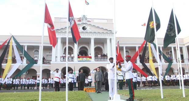 Everyone, including President Donald Ramotar and Prime Minister Samuel Hinds (fourth and third left, respectively), stands at attention as the Golden Arrowhead made its slow climb up the flagpole early yesterday morning on the forecourt of the seat of government, the Public Buildings