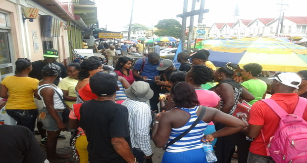 Vendors and other persons in the Stabroek Market area review a video of the entire ordeal yesterday afternoon