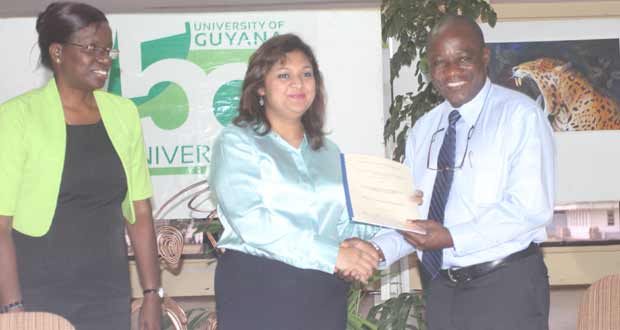 Education Minister, Ms Priya Manickchand hands over the relevant documentation to UG Vice-Chancellor, Professor Jacob Opadeyi