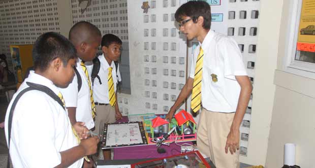A senior QC student explains the functioning of a solar powered system (Front page photo)
