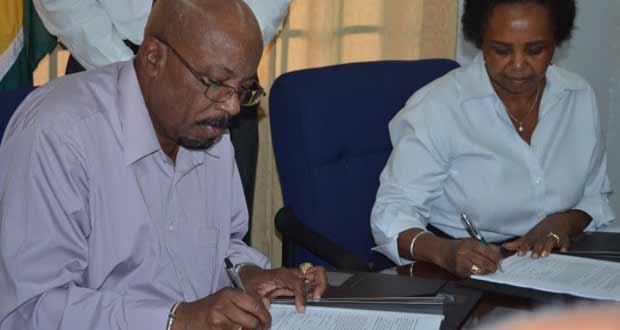 Minister of Local Government and Regional Development Norman Whittaker and United Nations Development Fund (UNDP), Resident Coordinator for Guyana; Khadija Musa signing the agreement