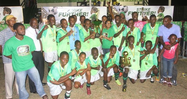 With his teammates celebrating behind him, Lodge Secondary School’s victorious captain Jarred Grannum proudly accepts the championship trophy from M. Beepat and Sons Brand Manager for Milo, Renita Sital. (Photo by Sonell Nelson)