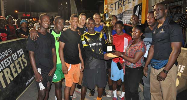 Eagles skipper Deron Smith receives the winning trophy and prize money from Banks DIH Linden Branch Manager Shondell Easton in the presence of Guinness Brand Manager Lee Baptiste (right), Outdoor Events Manager Mortimer Stewart and his teammates.