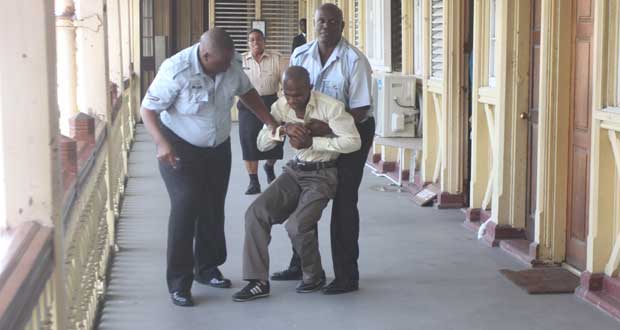 Police succeed in restraining a convicted Kevin Verwayne (in handcuffs) leaping to his death over the Court’s railing after learning he’d have to spend the rest of his life in jail