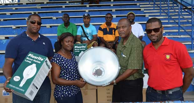 Shondell Easton, Banks DIH Linden Branch Manager presents one of the electric lamps to Secretary of the Mackenzie Sports Club, Robert Langevine while Region Ten Chairman Sharma Solomon, Mortimer Stewart and other officials look on.