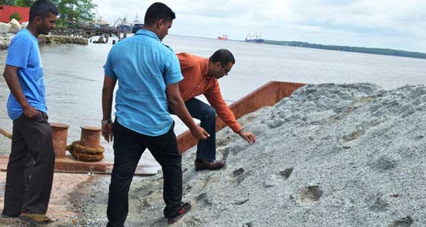 Minister of Natural Resources and the Environment, Mr. Robert Persaud, examines the stone whilst Mr Vishnu Ramdial of Durban Quarries looks on