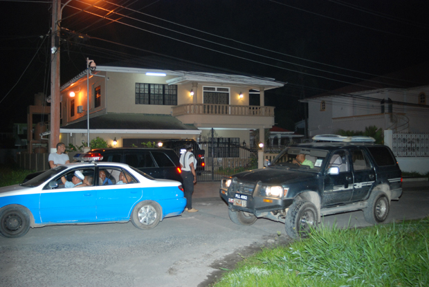 Police and GRA officers in front of Lot 8 Continental Park, East Bank Demerara, the address listed on the registration forms for both of the vehicles