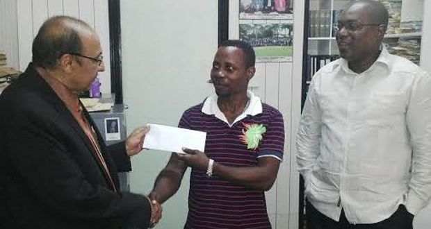GOA President KA Juman Yassin makes the presentation to coach Sebert Blake while GBA President Steve Ninvalle looks on.