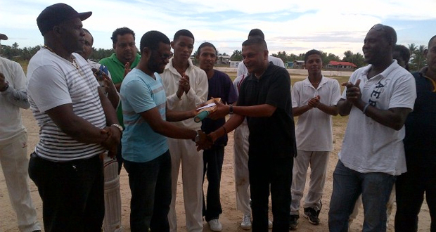 Regional Chairman of Region 10 Sharma Solomon (2nd left) receives the cheque and cricket bat from secretary of the GCB, Anand Sanasie, in the presence of Lancelot Easton (left) and TDO Colin Stuart (right) while other officials including Rohan Sarjoo and cricketers look on appreciatively.