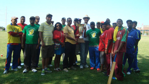 Ramesh Sunich (left) of Trophy Stall (Guyana) hands over the winning trophy to the East Division winning skipper Anand Goordial in the presence of executives, members and players of the OSCL.