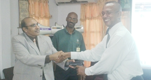 GOA President, K. A. Juman Yassin (left) hold the start gun of the FAT System with AAG President, Aubrey Hutson, while GOA Official Garfield Wiltshire (centre) looks on.