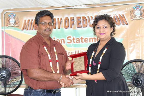 Education Minister Priya Manickchand presents Komal Singh with a plaque, in acknowledgement of his charitableness in accommodating the displaced students when the school was destroyed by fire