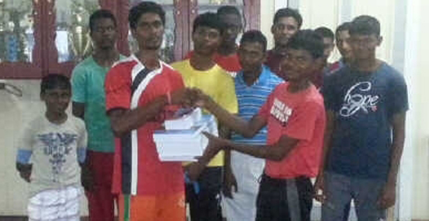 PMCC Under-17 skipper Daniel Samaroo (forefront right) is all smiles as he accepts his textbooks from Yogendra Harrinarine, in the presence of other club members.