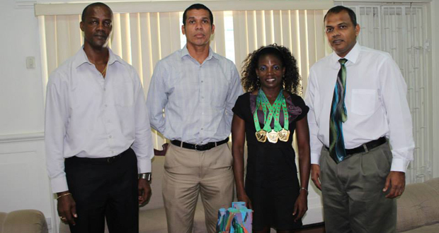 North, Central American and Caribbean World Masters Athletics Championships triple gold medal winner Alicia Fortune (2nd right), strikes a pose with Minister of Sport Dr Frank Anthony (right) Permanent Secretary Alfred King (left) and an executive of the Guyana Masters Association.