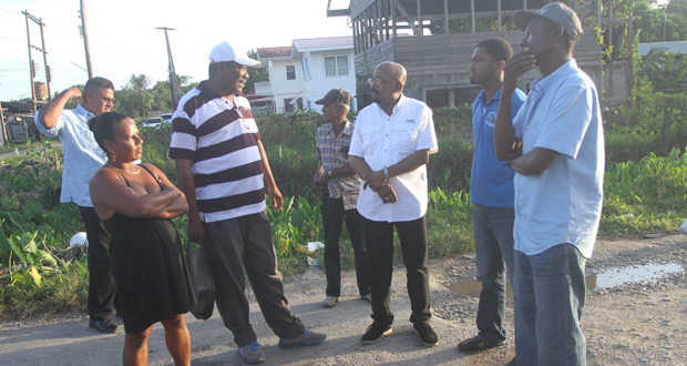 Minister of Local Government and Regional Development, Mr. Norman Whittaker examines the reduced flow of the Mon Grepo Creek with IMC Chairman, Mr. Ovid Benjamin