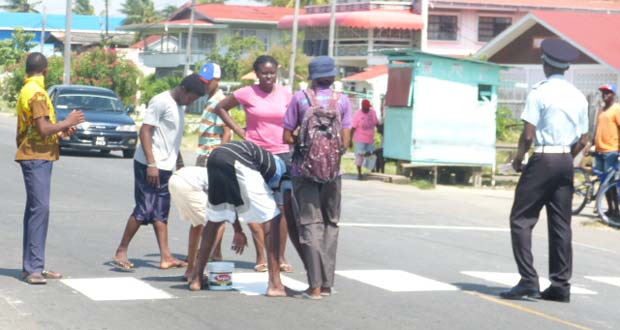 Members of the Seventh Day Adventist Church in Berbice paint a pedestrian crossing.
