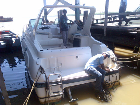 This Leroy Smith photo dated October 2013, shows two employees from the boathouse in Georgetown examining the vessel which the police handed over to the Maritime Administration Department