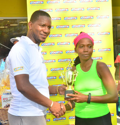 COURTS Marketing Manager Pernell Cummings presents Euleen Josiah-Tanner with her trophy after winning her fourth successive 10K Road Race.
(Adrian Narine Photos)