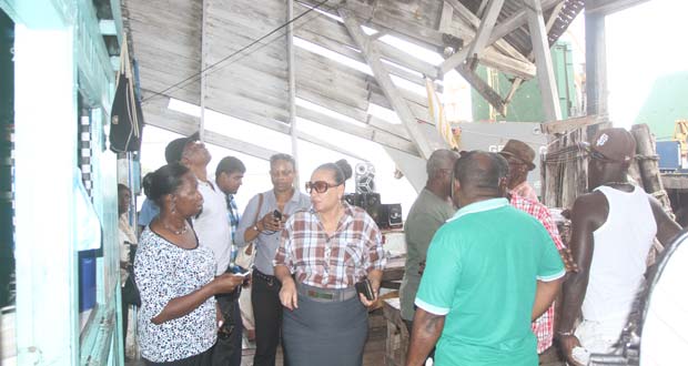 Deputy Mayor, Patricia Chase Green (at centre) and team along with journalists under the collapsed roof at Stabroek Market wharf