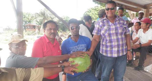 Minister Alli Baksh with cash crop farmer Andy Patrick [blue jersery] and other farmers of Lima Sands holding a large, healthy water melon that was grown in the village