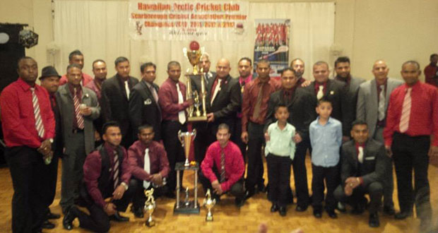 HACC president Archie Mohan and skipper Hemnarine Chattergoon pose with the Premier League trophy in the presence of other players, officials and supporters.