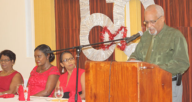 Seated from left at the RNCF Dinner: Treasurer, Ms. Doris Lewis; Minister Jennifer Webster (centre) and RNCF Chair, Mrs. Molly Hassan. At the podium is emcee and veteran broadcaster Ron Robinson