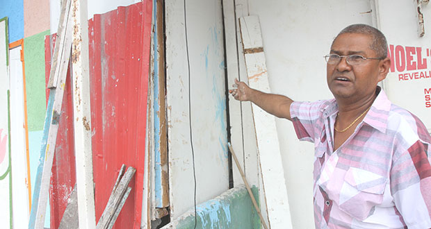 Businessman Looknarine Basdeo points to the area where the bandits gained entry to his building.