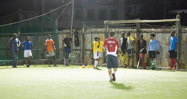 Coach Robert Fernandes (L) explains plays to the National U-19s on the GCC ground, Bourda. At right is Dwayne Alleyne.