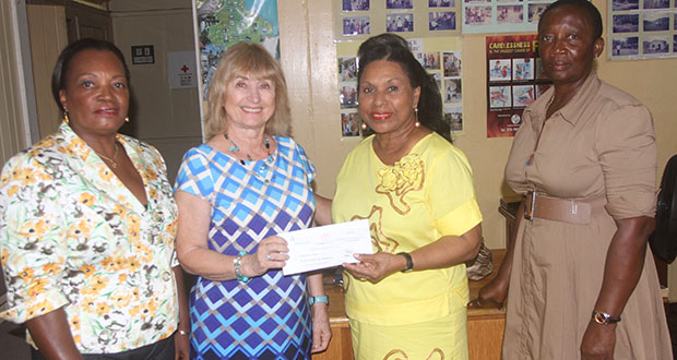 Mrs. Yvonne Hinds (right) receives the cheque of $1.1M from Ms. Agnes Mundal