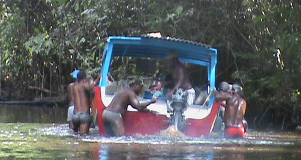 Low water level in the areas of Dark Bush and 99 Turns has caused miners serious problems. In picture, a group of miners struggle to get their boat across to deeper water.