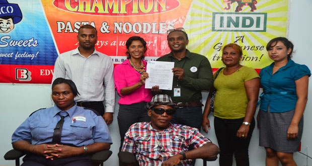 Edward B Beharry’s Director, Anjuli Beharry-Stand and Habitat’s Director Rawle Small surrounded by staffers and beneficiaries