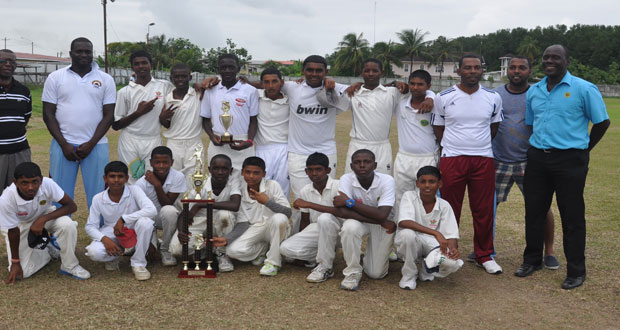 The winning Berbice Under-15 team pose with the championship trophy in the presence of their manager and coach and other Board officials.