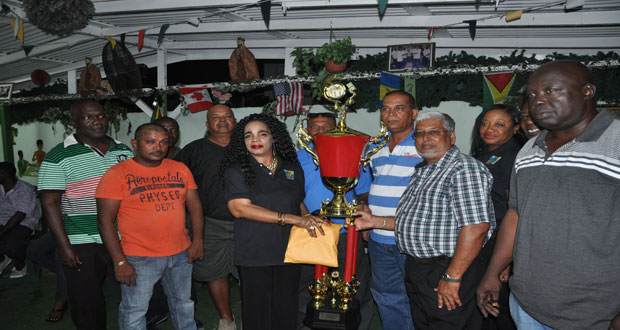 GDA president Fay Joseph hands over the winners’ trophy and the US$5 000 to a representative of Rage Dominoes team while other members look on.
