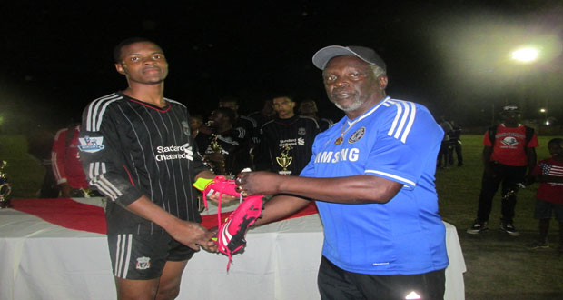 Canada-based Edward 'Screw' Richmond member James 'Gads' Dennis at right hands over a new pair of football boots to top goalscorer Shane Lucky of Christianburg Wismar Secondary School.