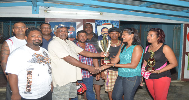 RAMROOP ‘Spoon’ Sukhai receives the winning trophy from Indra Jagmohan in the presence of other members of the winning team.