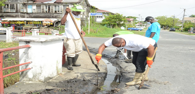 GNNL’s General Manager Michael Gordon and staff members cleaning along Vlissengen Road yesterday (Delano Williams photos)