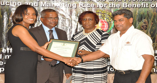 Ms. Sharonmae Shirley hands over the award to Chairman of the Board of Directors of the GRDB, Mr. Badrie Persaud, in the presence of Mr. Singh and Ms. Allison Peters