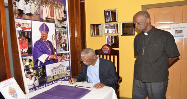 President David Granger signing the Book of Condolence for the late Anglican Bishop of Guyana, Rt. Rev. Cornell Moss. Looking on at right is Vicar-General Oscar Bazil