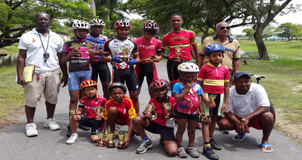 Prize winners of the various categories strike a pose with national cycle coach Hassan Mohamed (extreme right standing) and race director Joseph Britton (extreme left). Second left standing is Johnathan Jagdeo, Jamal John is second right and Leung is standing at third right.