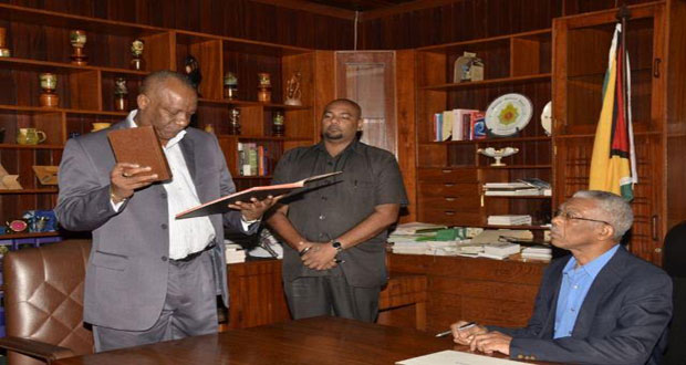 Mr. Joseph Harmon, Minister of State, takes the oath of office as Secretary to the Defence Board before President David Granger