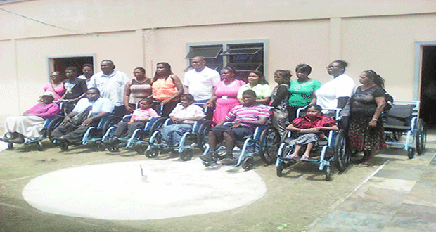 Recipients of the wheelchairs pose for a photograph with their relatives and Messrs Jameel Davis and Alex Foster of the FFTP