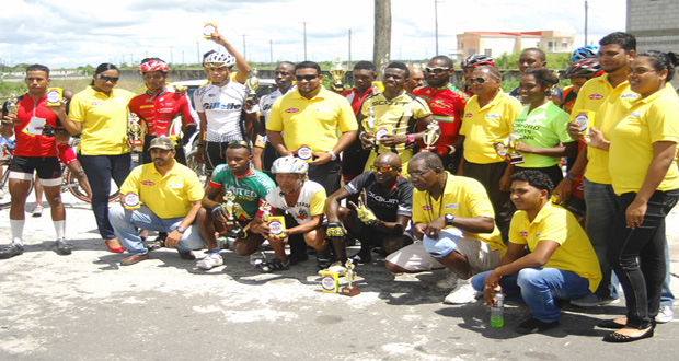 Prize winners of the various categories of yesterday’s Dr. Chase/Massy Distribution Inc. sponsored 50-mile cycle road race strike a pose with the sponsors’ Pharmaceutical Manager Karen Connell (second left) and the company’s Product Representative Claude Dhanraj (standing at centre).