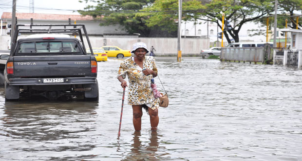  An elderly woman negotiates her way through flooded Middle Street, Georgetown